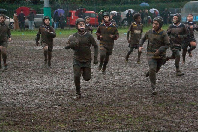 Un gruppo di bambini sta correndo in un campo fangoso.