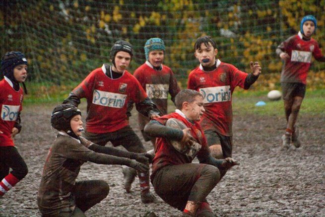 Un gruppo di ragazzi sta giocando una partita di rugby nel fango.
