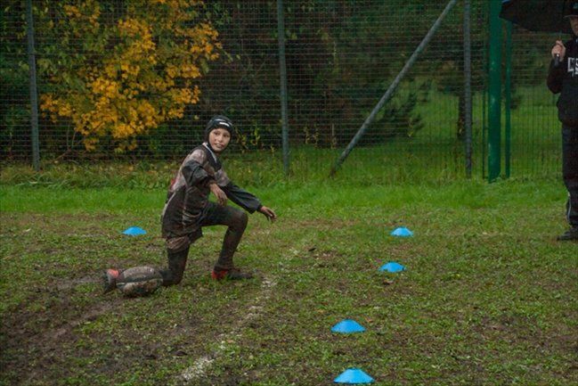 Un ragazzino è inginocchiato sull'erba in un campo.