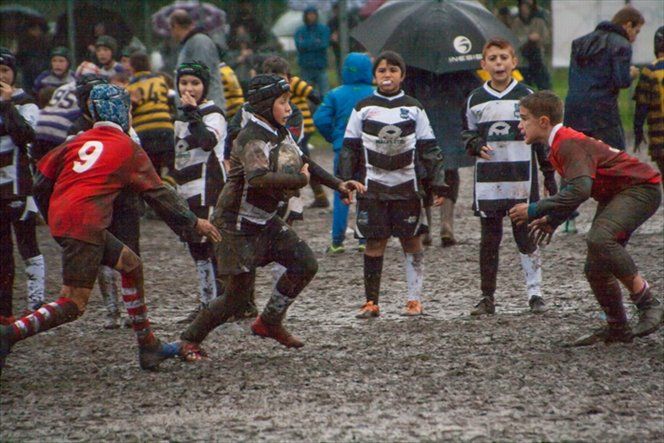 Un gruppo di ragazzi sta giocando una partita di rugby sotto la pioggia.