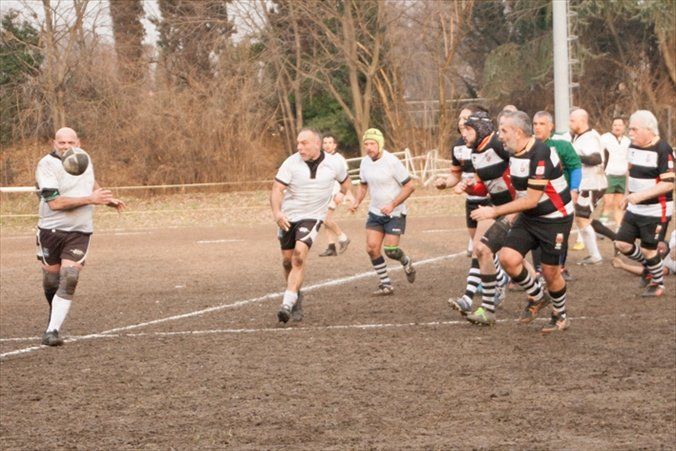 Un gruppo di uomini sta giocando una partita di rugby su un campo fangoso.
