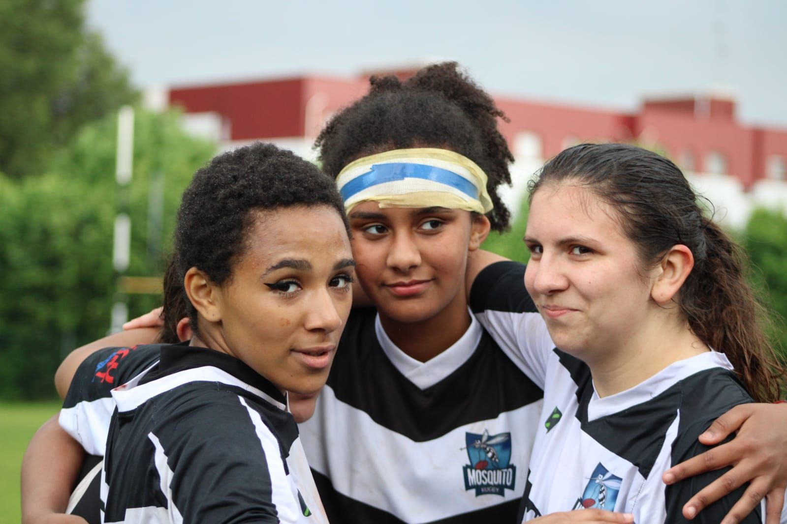 Tre giocatrici di rugby posano insieme per una foto.