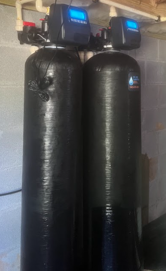 Two black water filtration tanks with digital displays, set against a pale wall.