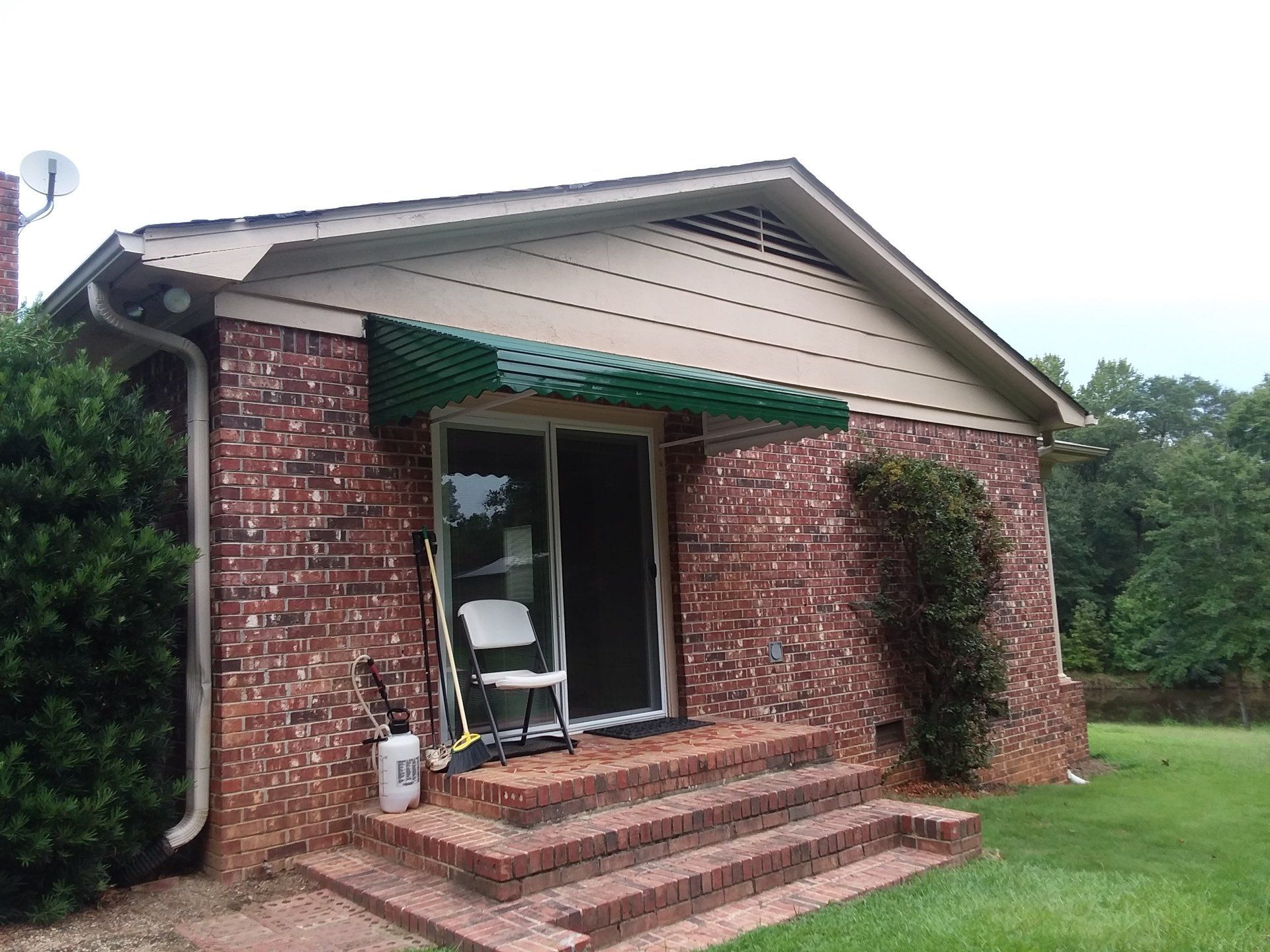 Green aluminum awning installed on brick home