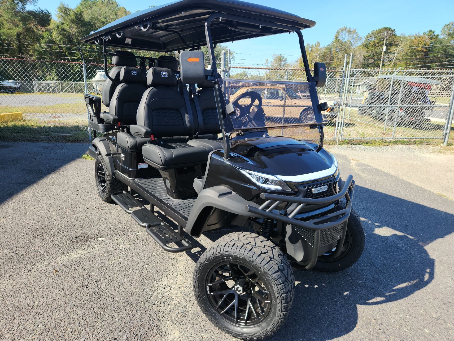 A black golf cart is parked in a parking lot.