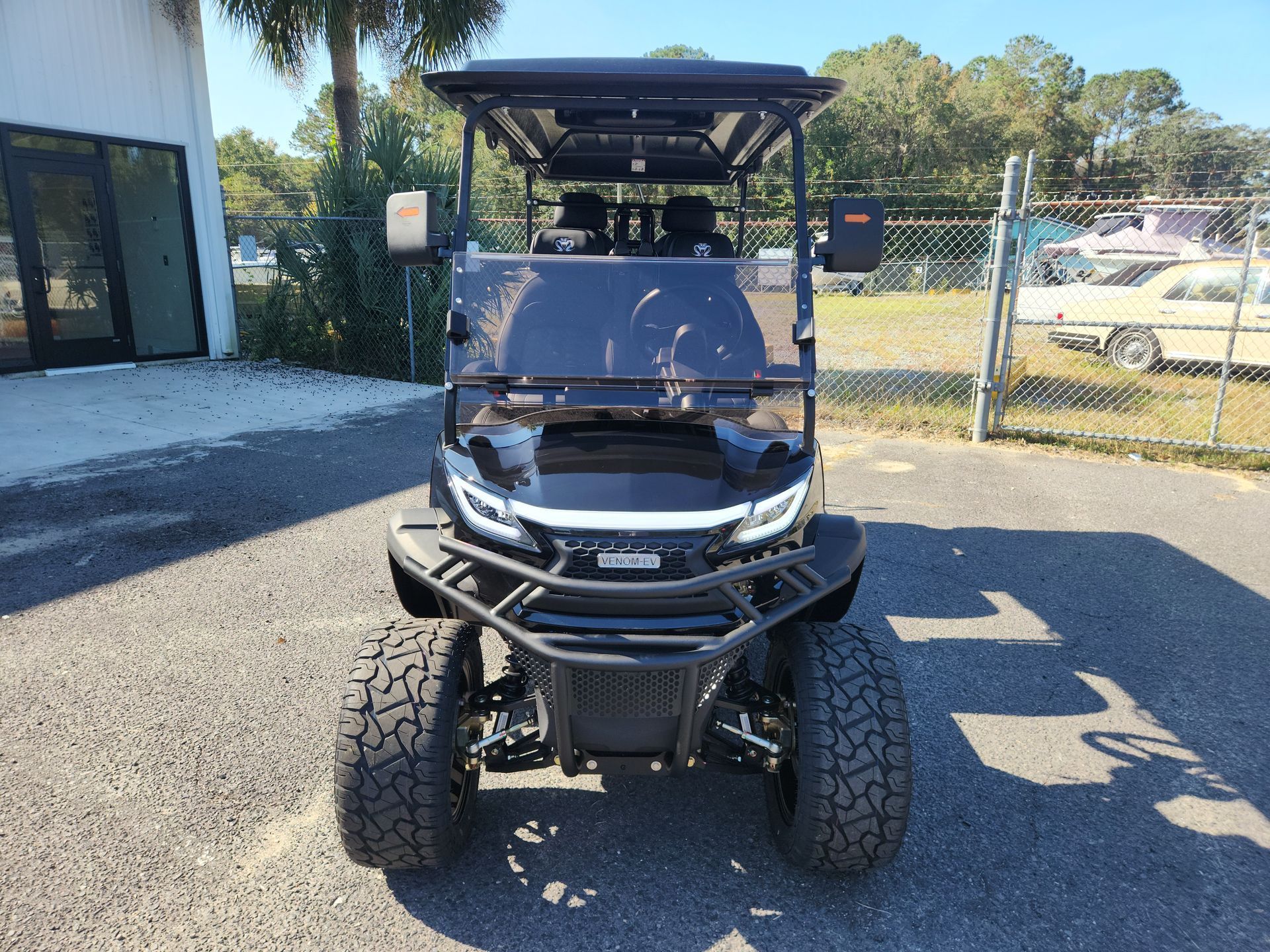 A black golf cart is parked in a parking lot.