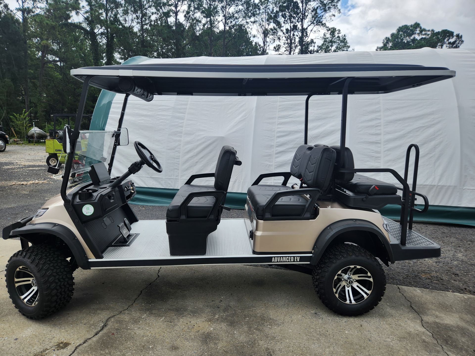 A golf cart is parked in front of a tent in a parking lot.