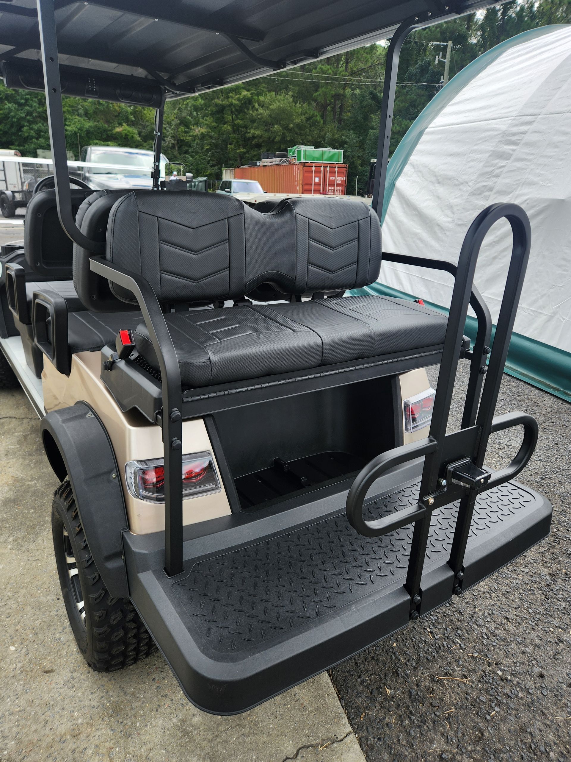 A golf cart with a black seat is parked in front of a tent.