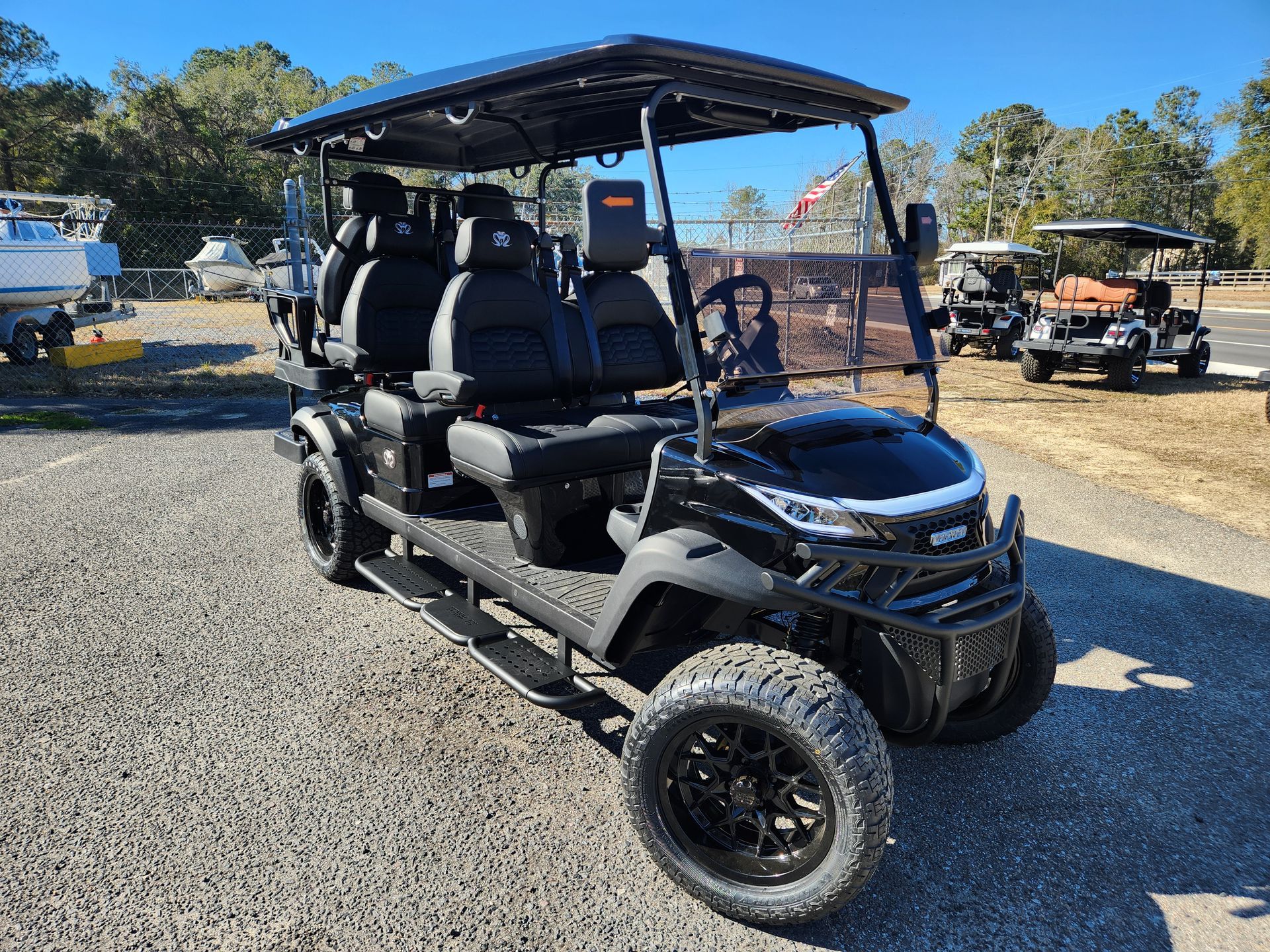 A black golf cart is parked in a gravel lot.