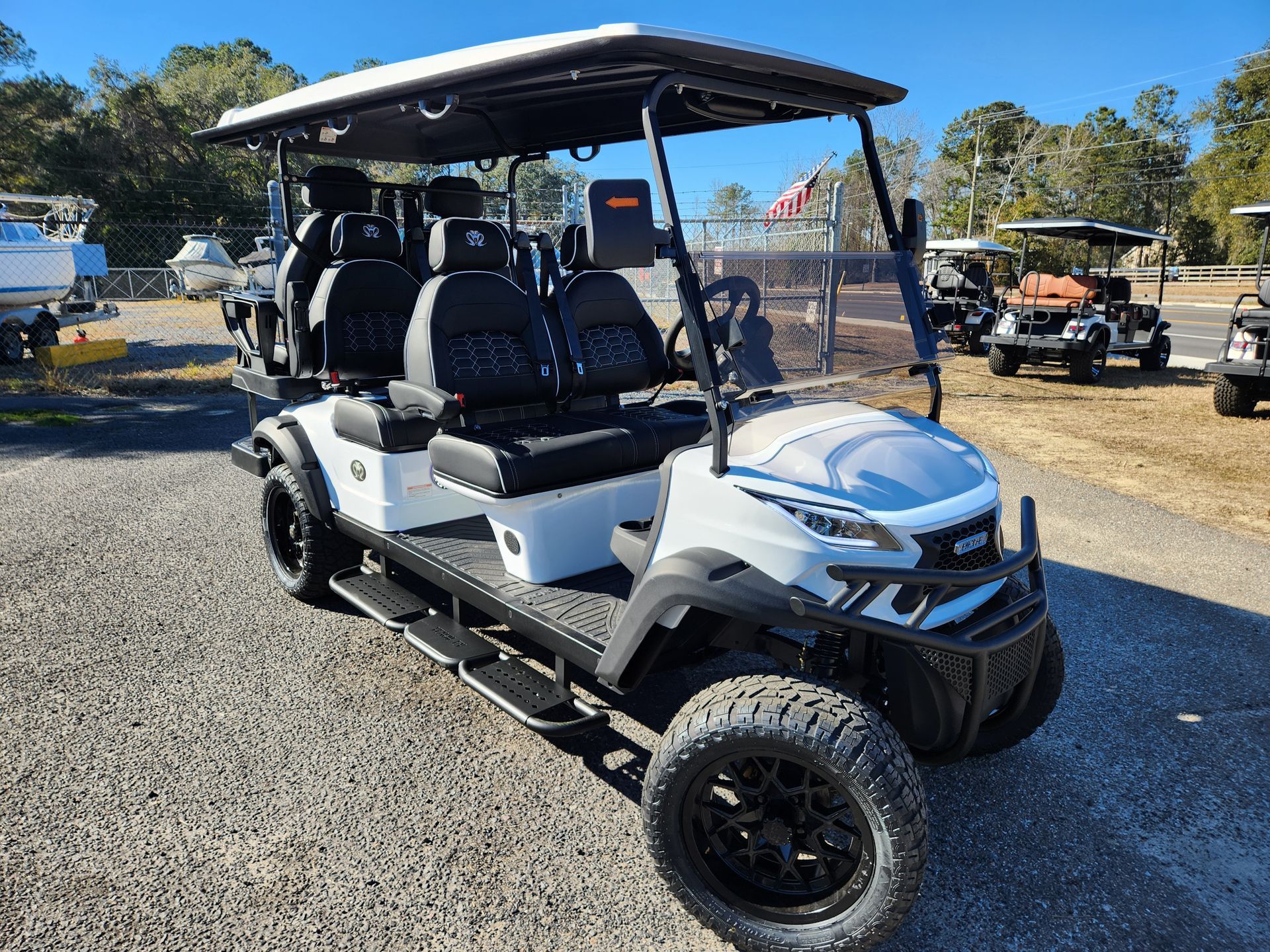 A white golf cart is parked in a gravel lot.