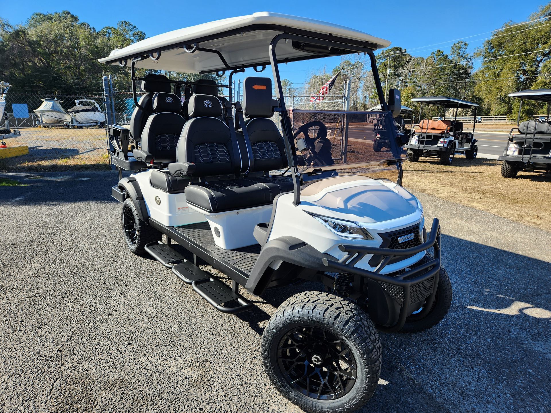 A white golf cart is parked in a gravel lot.
