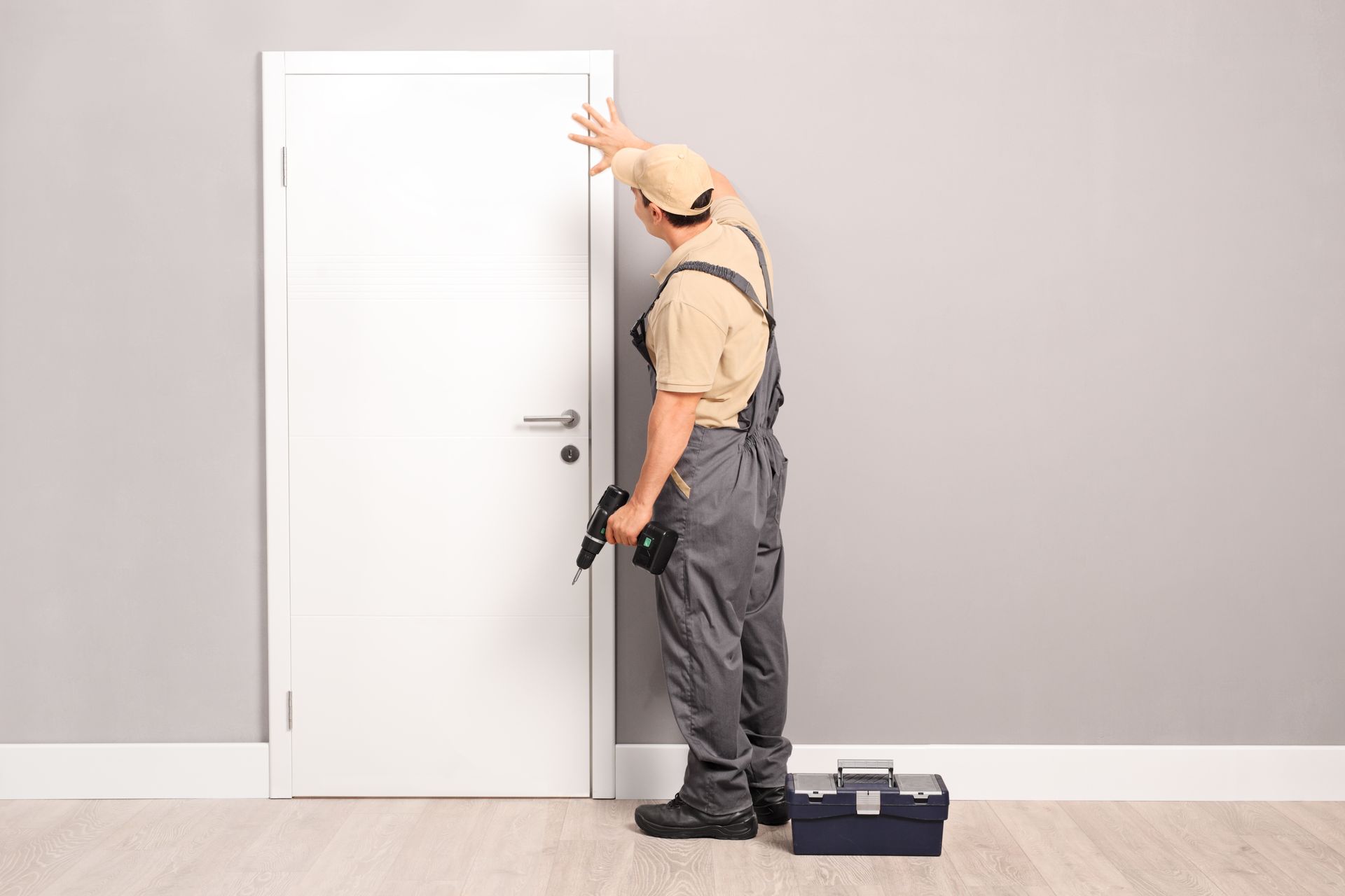 Contractor installing an interior door using a power drill during a residential renovation project.