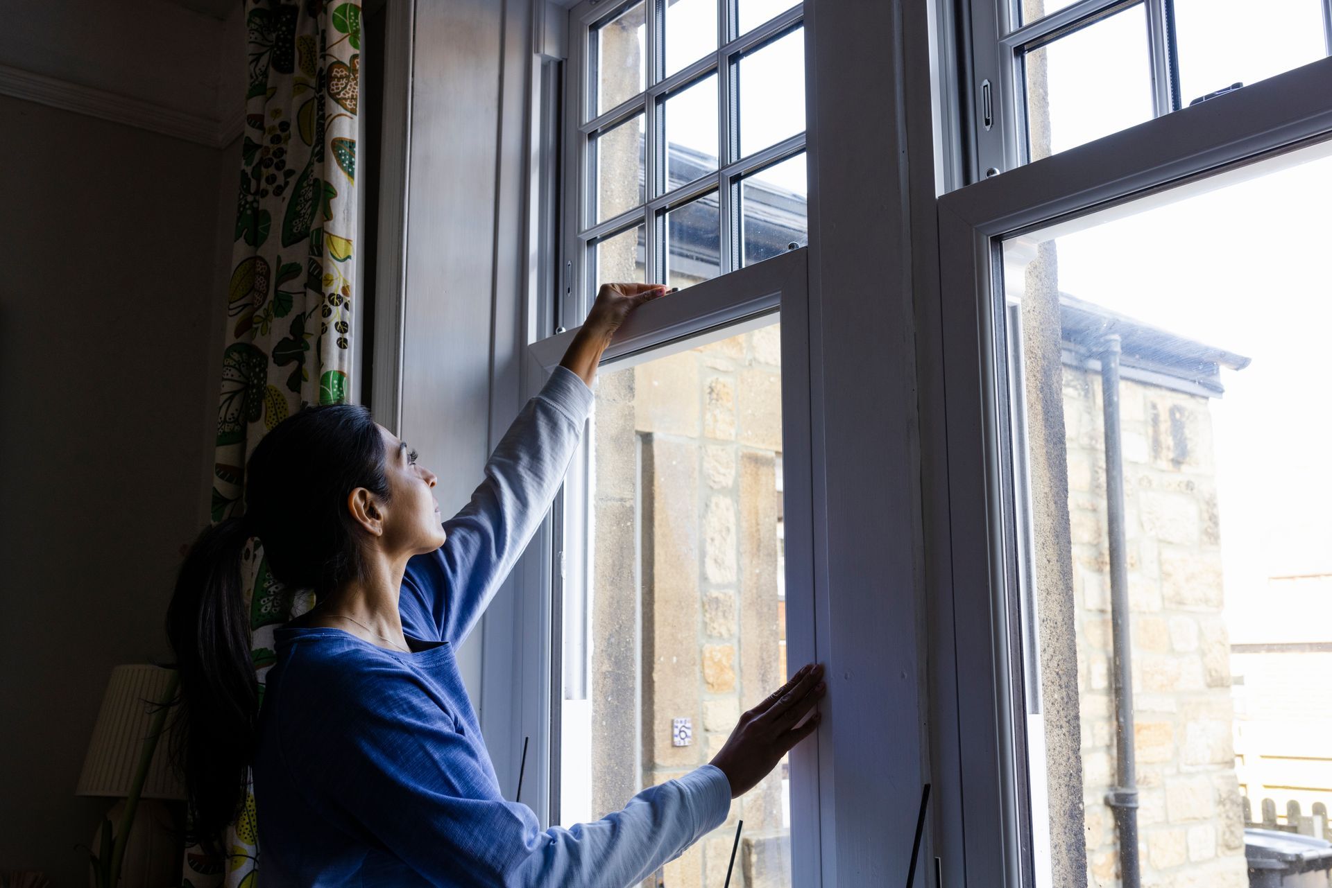 Woman shuts her new double-glazed windows, showcasing quality new window installation.