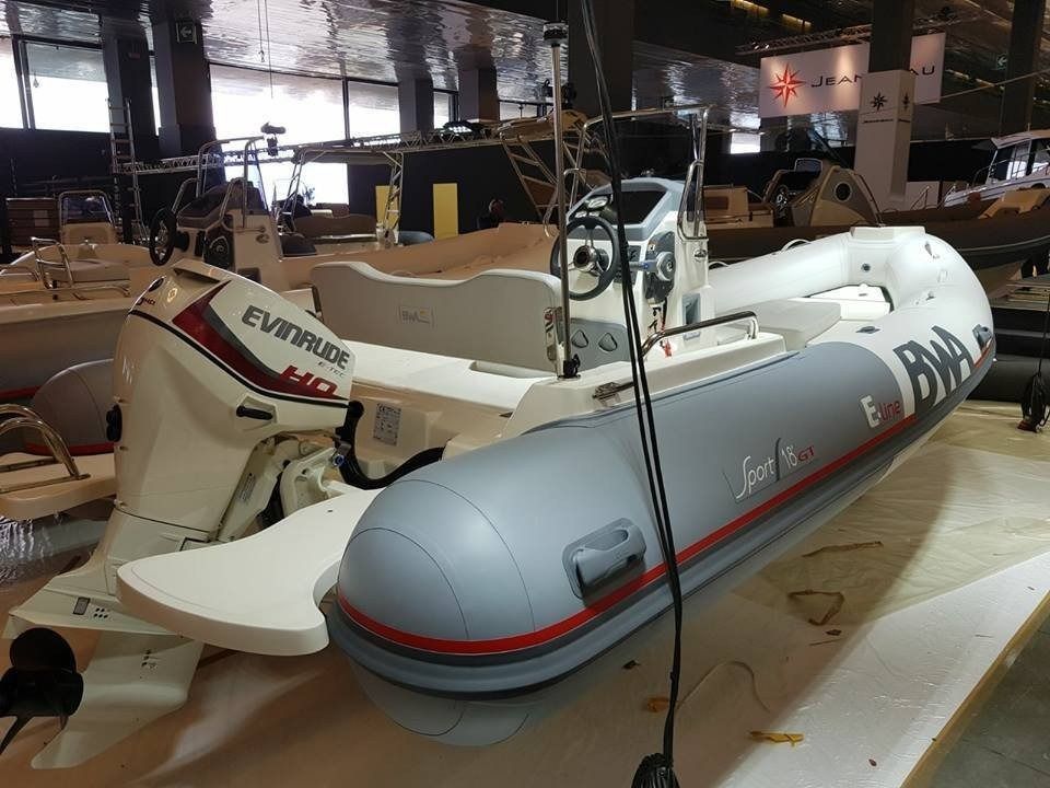 Barca gonfiabile grigia e bianca con motore Evinrude, all'interno di un edificio.