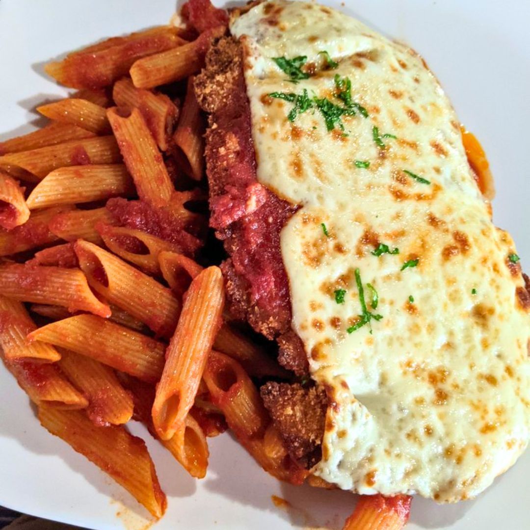 A plate of pasta with meat and cheese on top