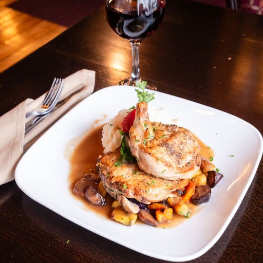 A plate of food on a table next to a glass of wine