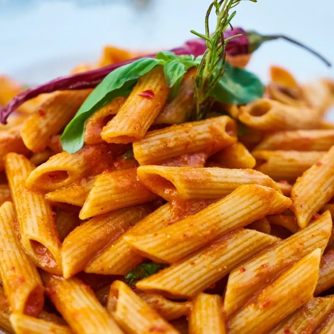 A close up of a plate of pasta with tomato sauce and basil