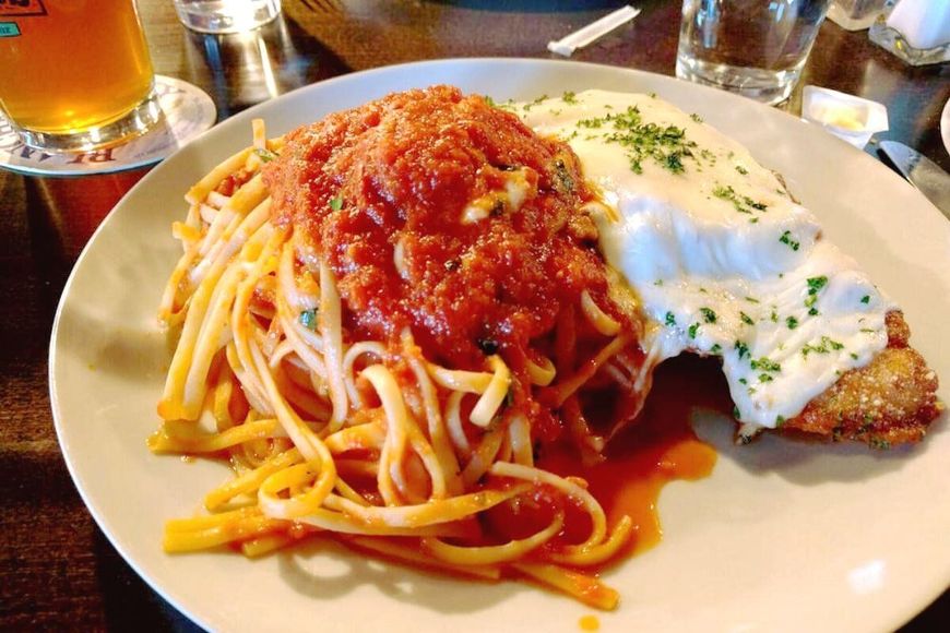 A white plate topped with spaghetti and meat on a table.
