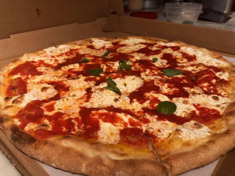 A pizza with tomato sauce and cheese is in a cardboard box.