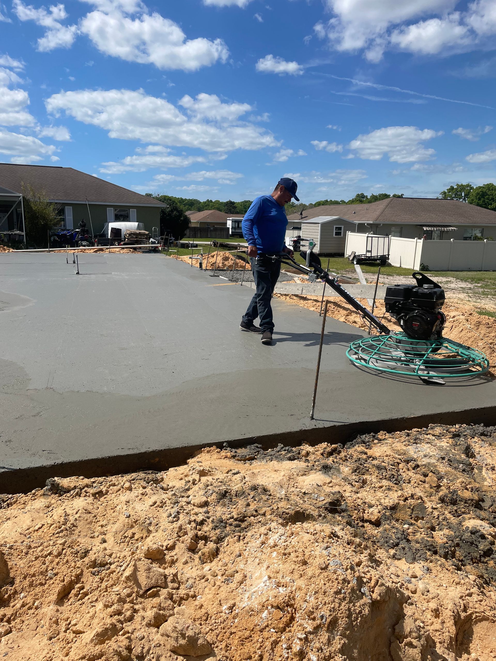 A man is using a machine to spread concrete on a construction site.