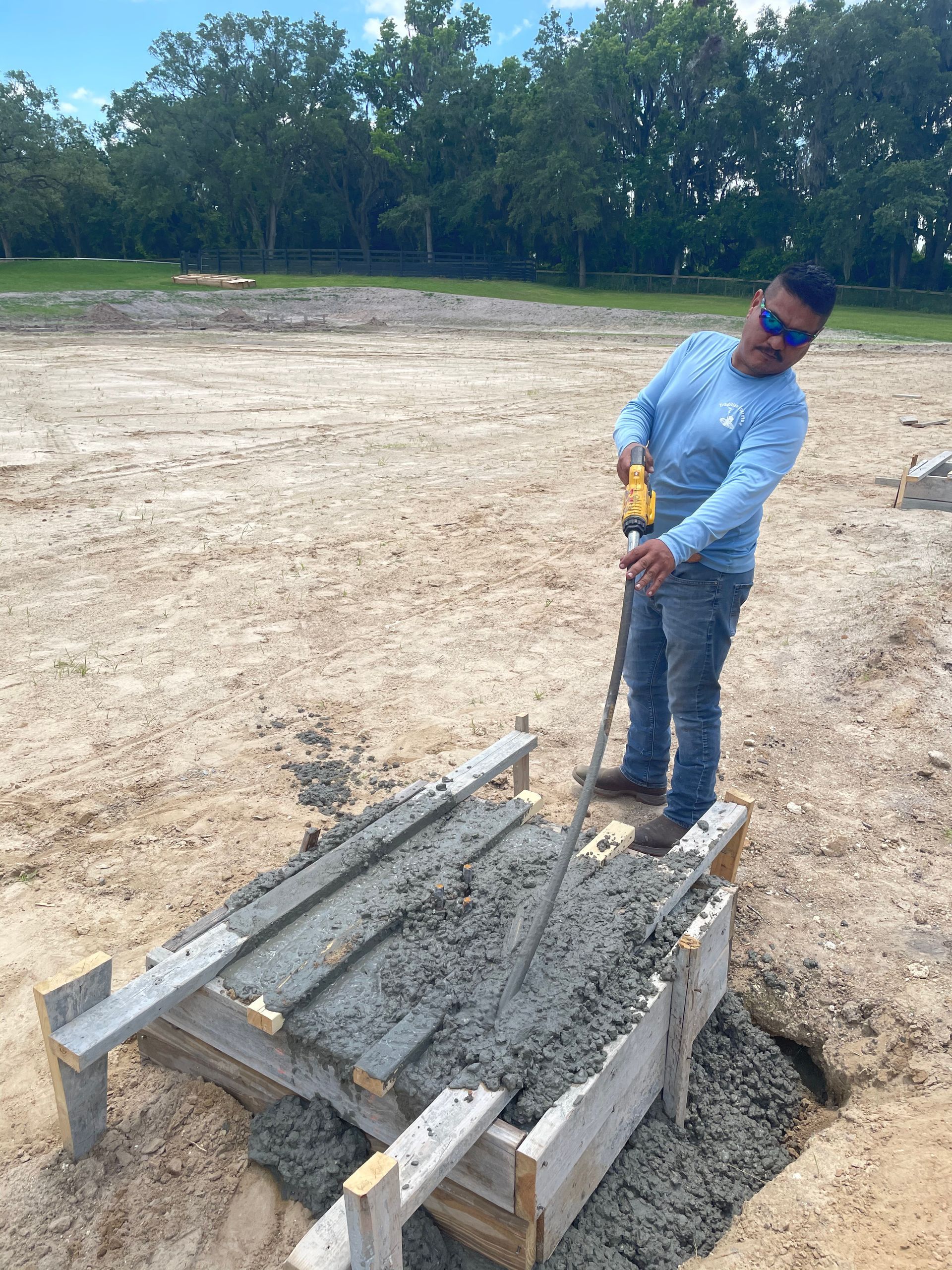 A man is standing next to a wooden pallet filled with concrete.