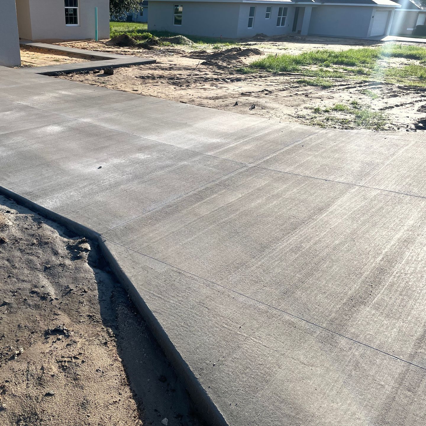 A large white house with a black garage door and concrete driveway. Project done by C1 Foundations in Ocala FL