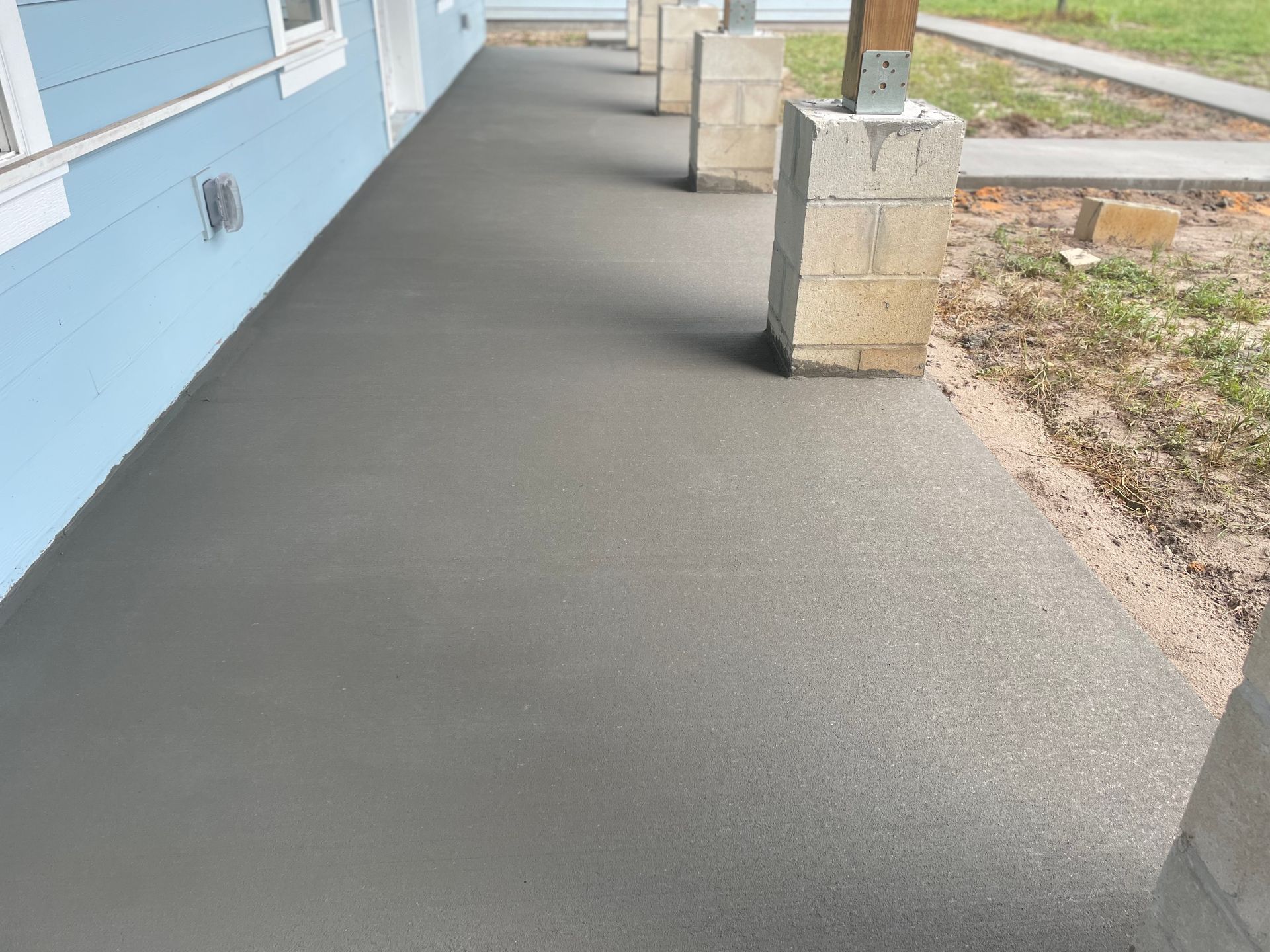A concrete walkway with a blue house in the background.