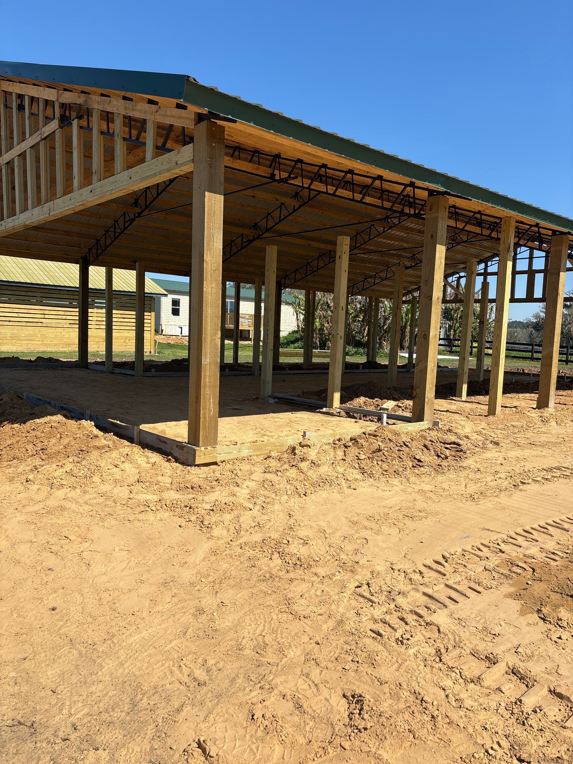 A large wooden structure is being built in the middle of a dirt field. By C1 Foundations in Ocala, Fl