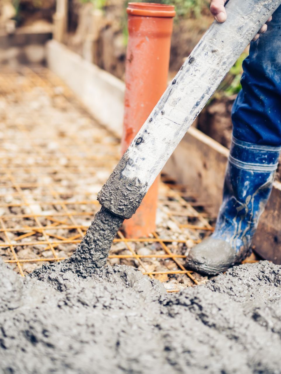 A person is pouring concrete into a hole in the ground.