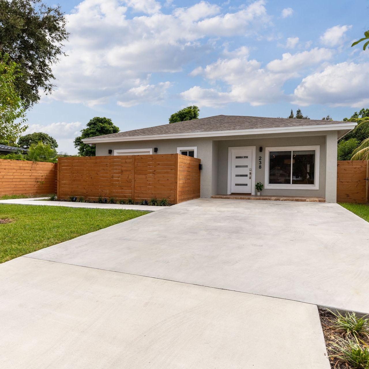 A large white house with a black garage door and concrete driveway.