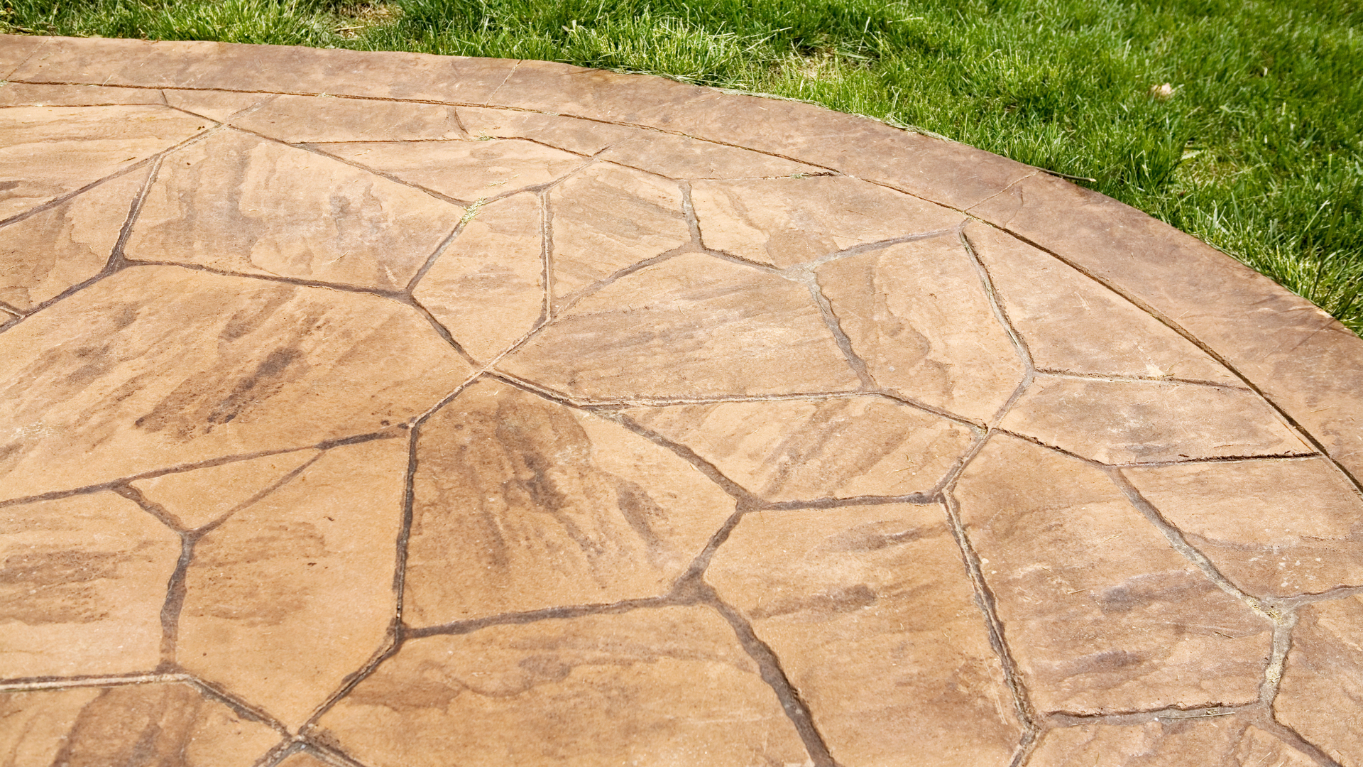 Stamped concrete patio with stone pattern texture and natural color finish in residential backyard