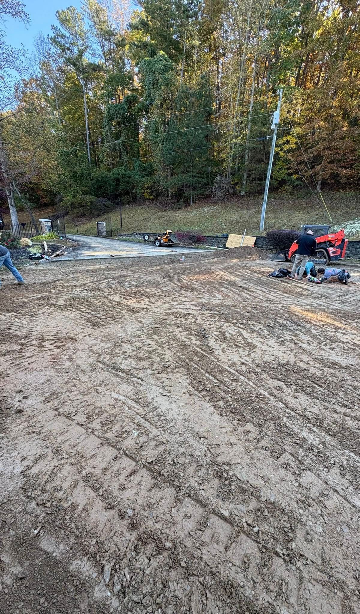 Cleared dirt lot with construction equipment and trees along the edge