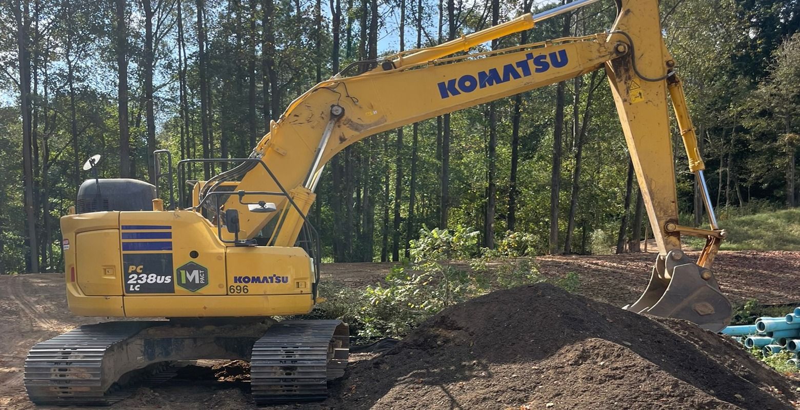 Yellow Komatsu excavator on tracks moving dirt in a wooded area