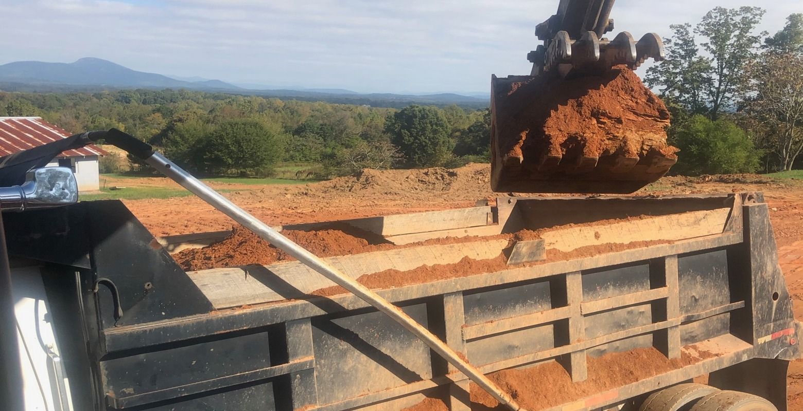 Rusty excavator bucket on a construction truck with a long metal bar, outdoors under clear sky
