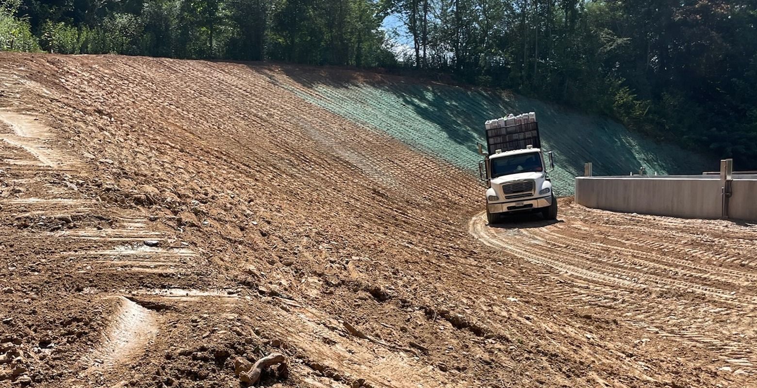Dump truck on a gravel slope at a construction site with trees in the background