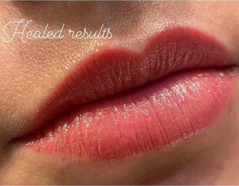 Woman getting eyebrow microblading, being worked on by gloved hands, indoors.