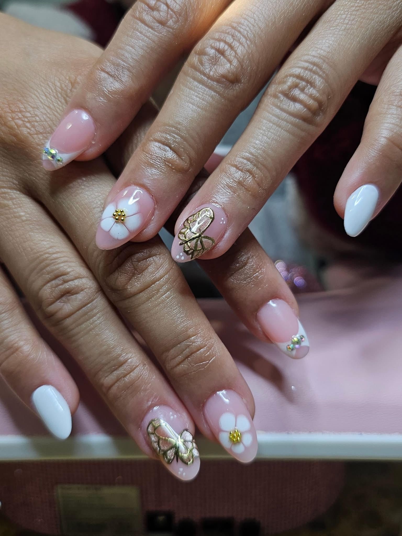 Hands with light pink and white oval-shaped nails; some have flower and gold leaf designs.
