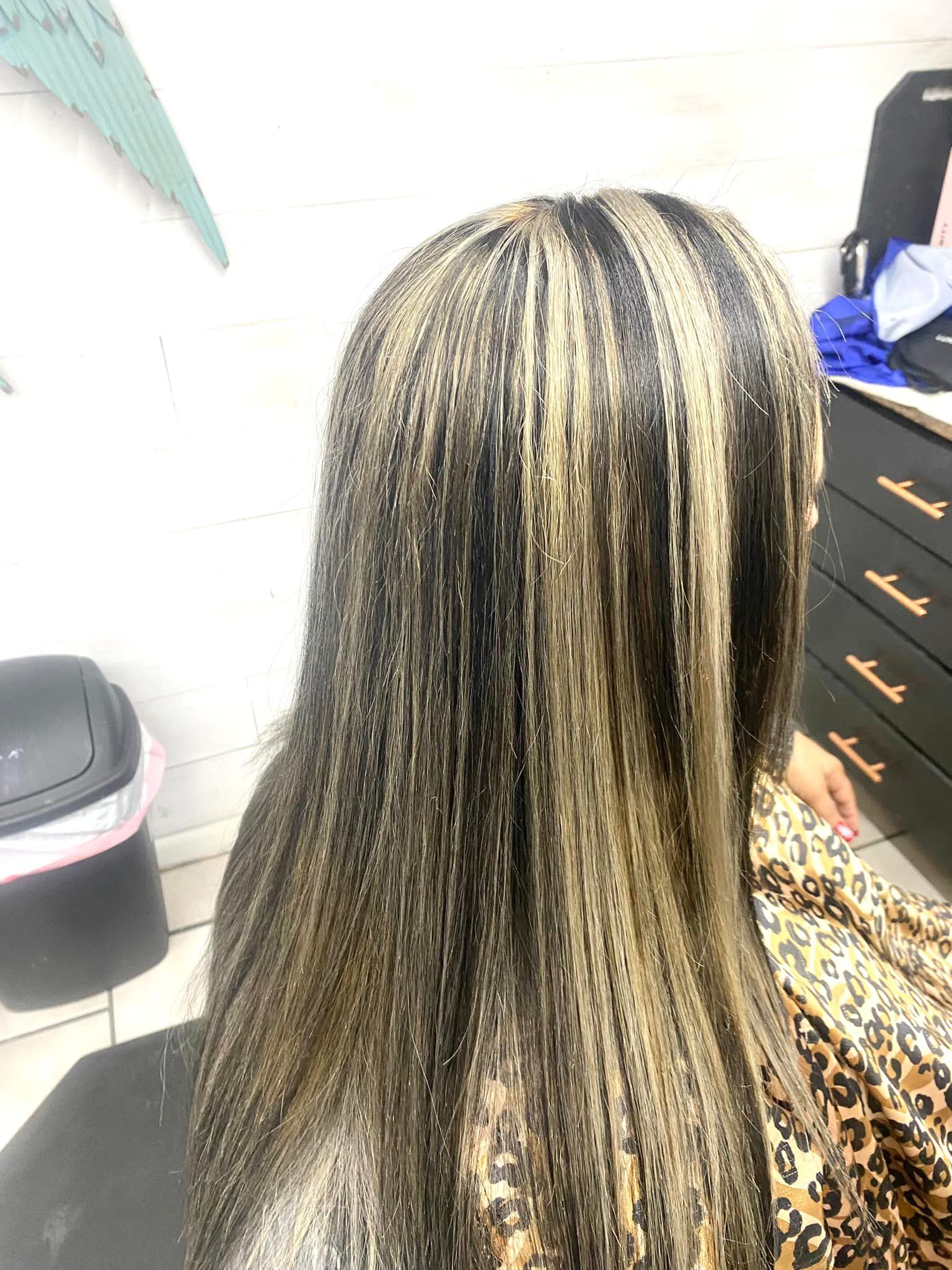 Woman with long, black and blonde hair extensions. Sitting in a salon.