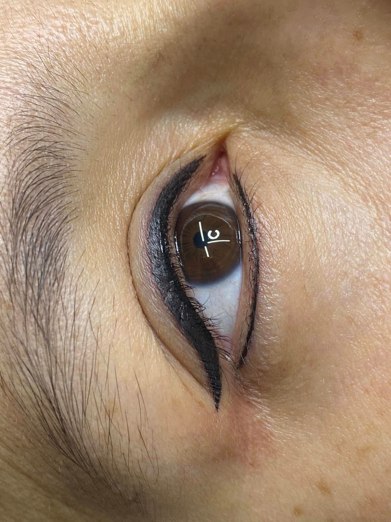 Close-up of an eye with permanent eyeliner. The dark eyeliner creates a wing shape. Brown eye, fair skin.