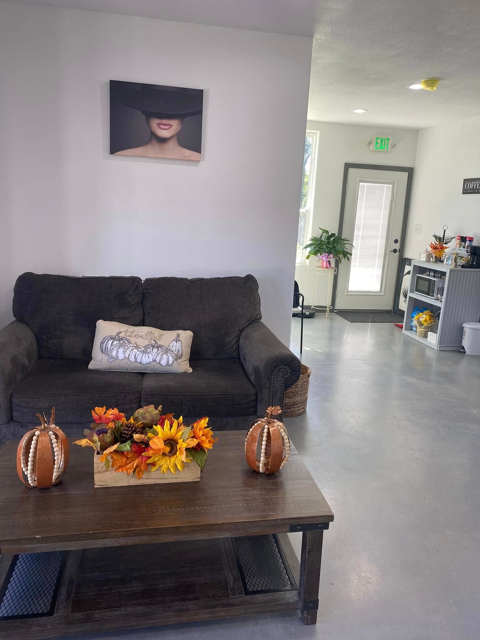 Living room with dark sofa, coffee table, and fall decor. Doorway leads to another room.