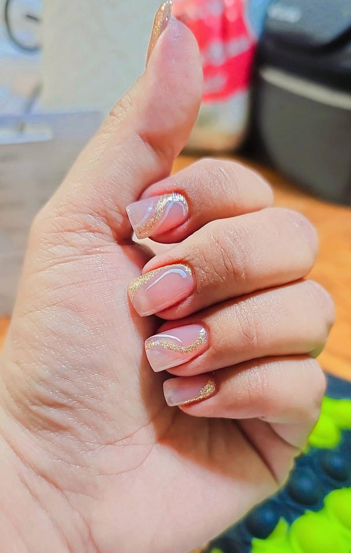 Hand with pink and gold manicured nails, thumb up.