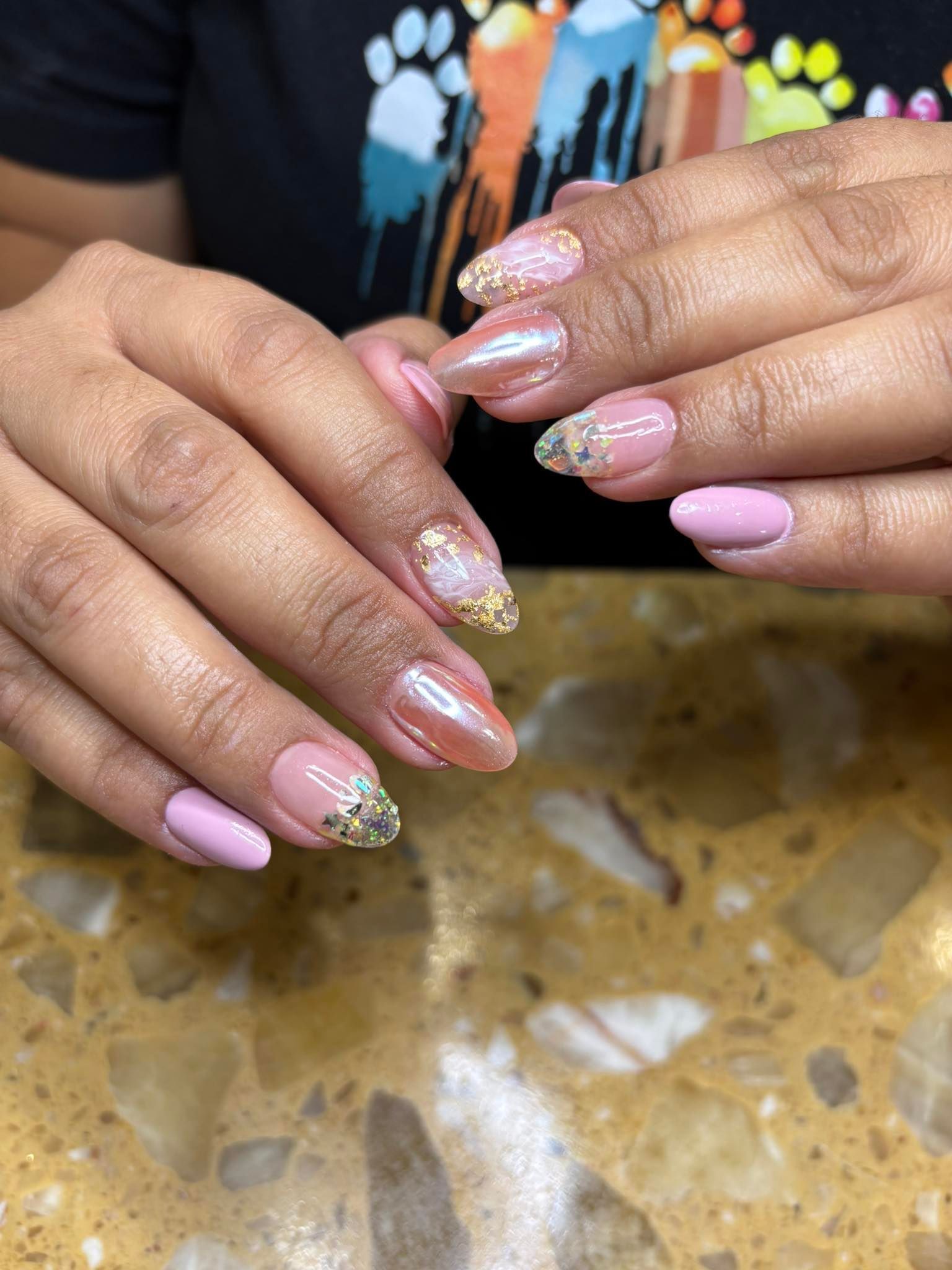 Hands with pink and gold gel nail designs.