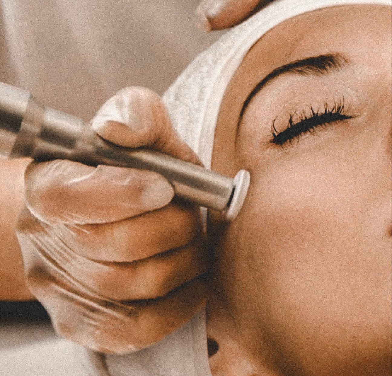 Person getting eyeliner tattoo applied near the eye; pink pencil in use.