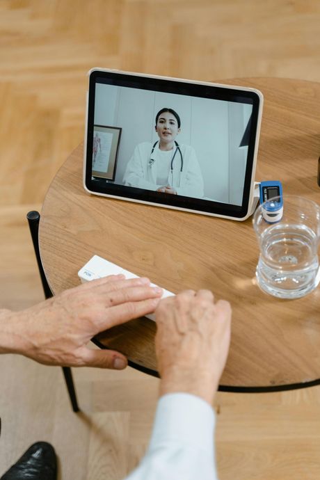 Person in video call with doctor on tablet, examining medicine box.