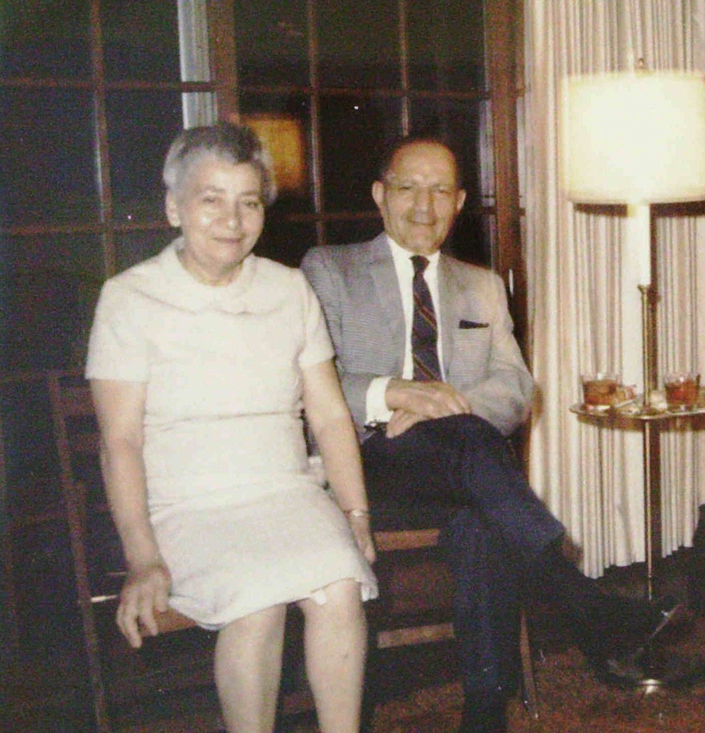 A man in a suit and tie sits next to a woman in a white dress