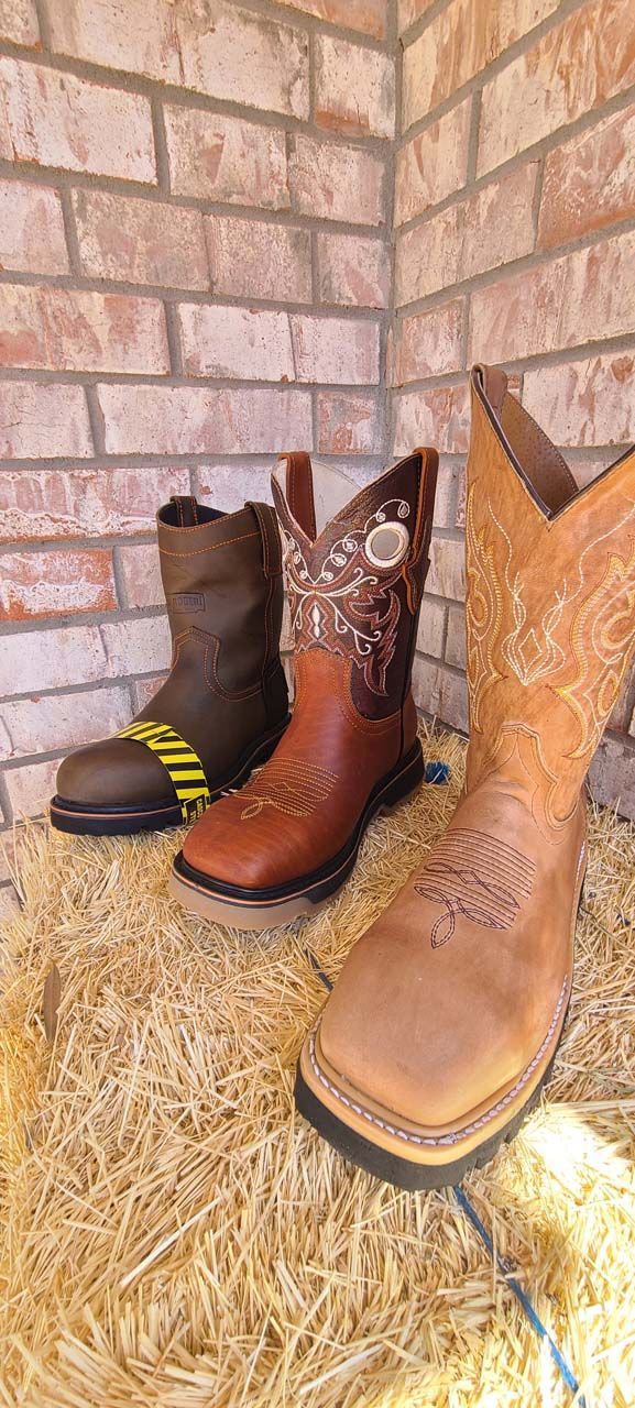 Three pairs of cowboy boots are sitting on top of a pile of hay.