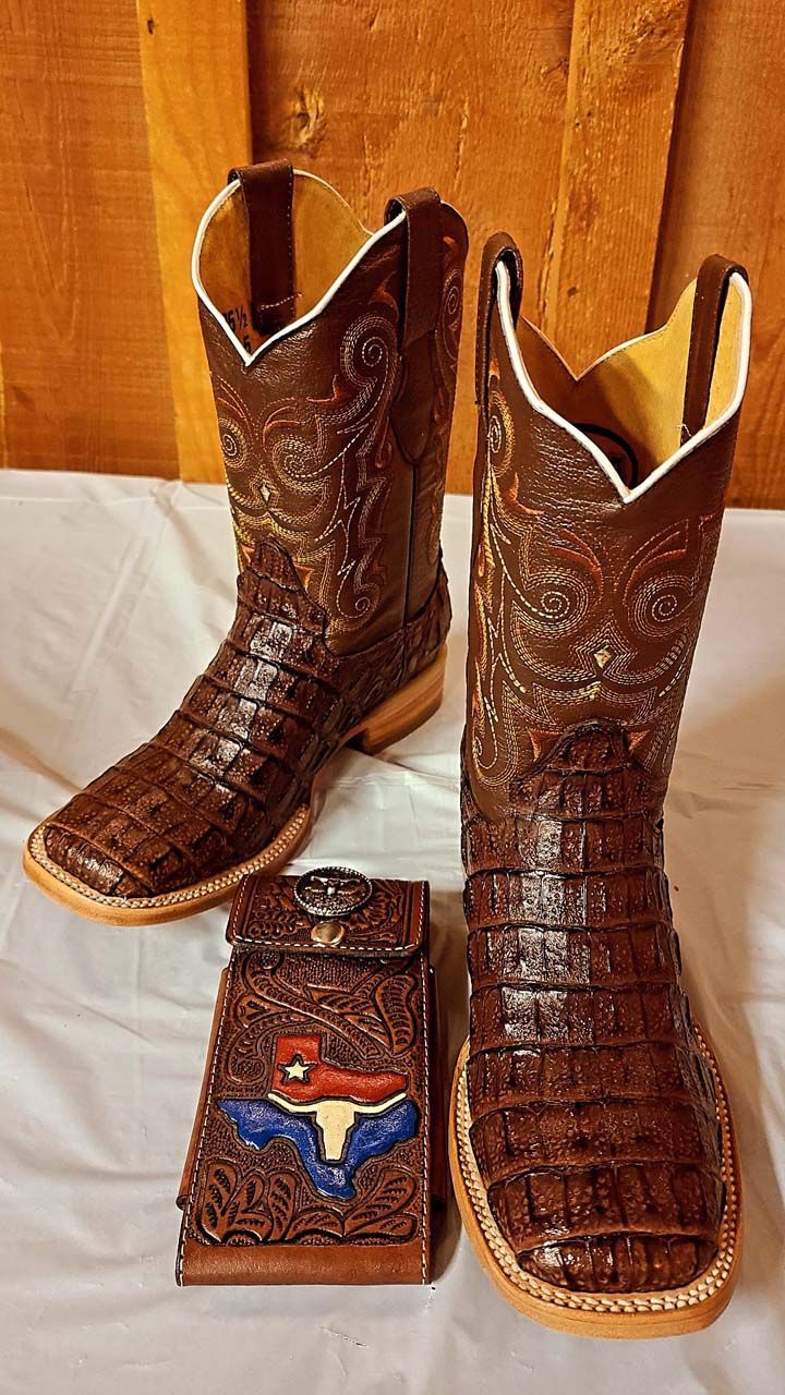 A pair of brown cowboy boots and a wallet are sitting on a table.