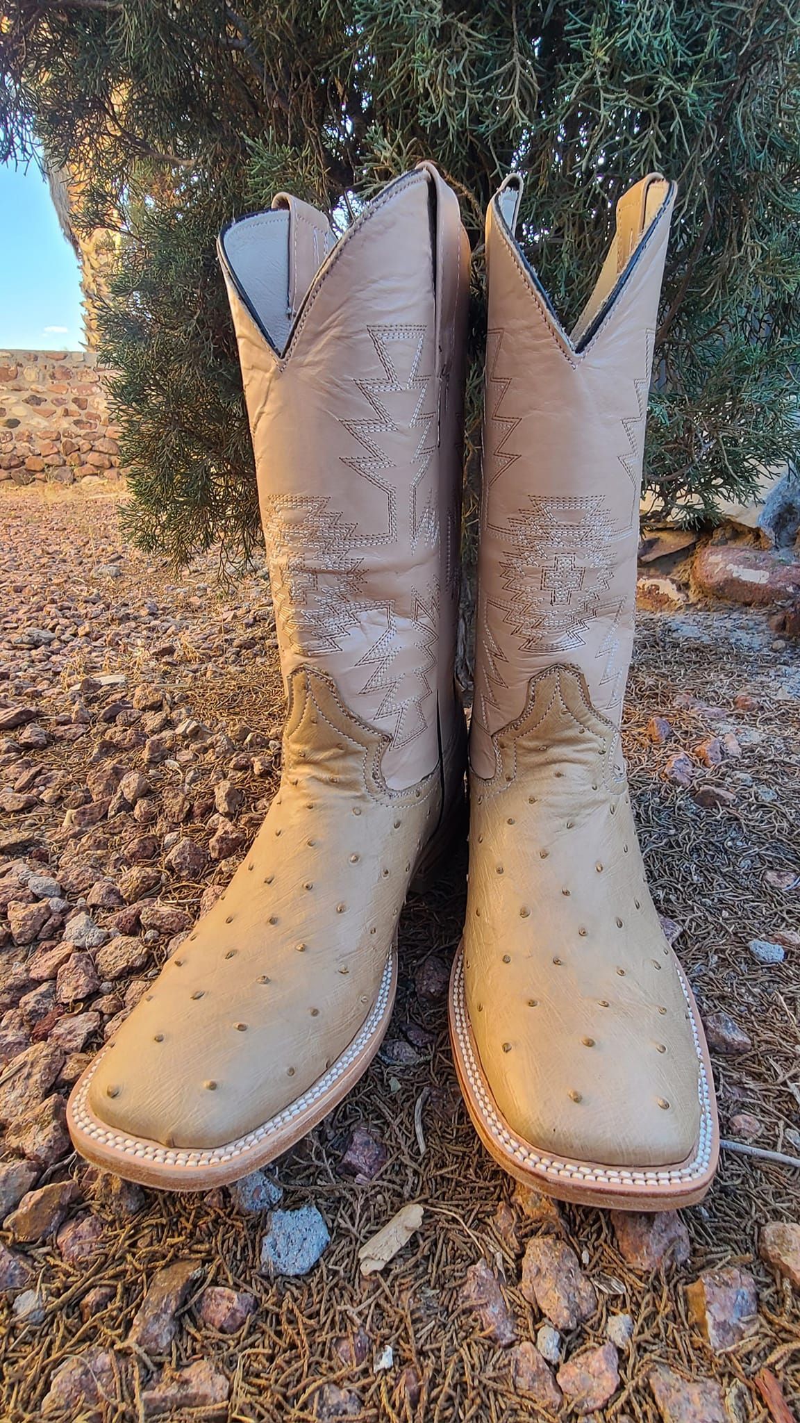 A pair of cowboy boots are sitting on top of a pile of rocks.
