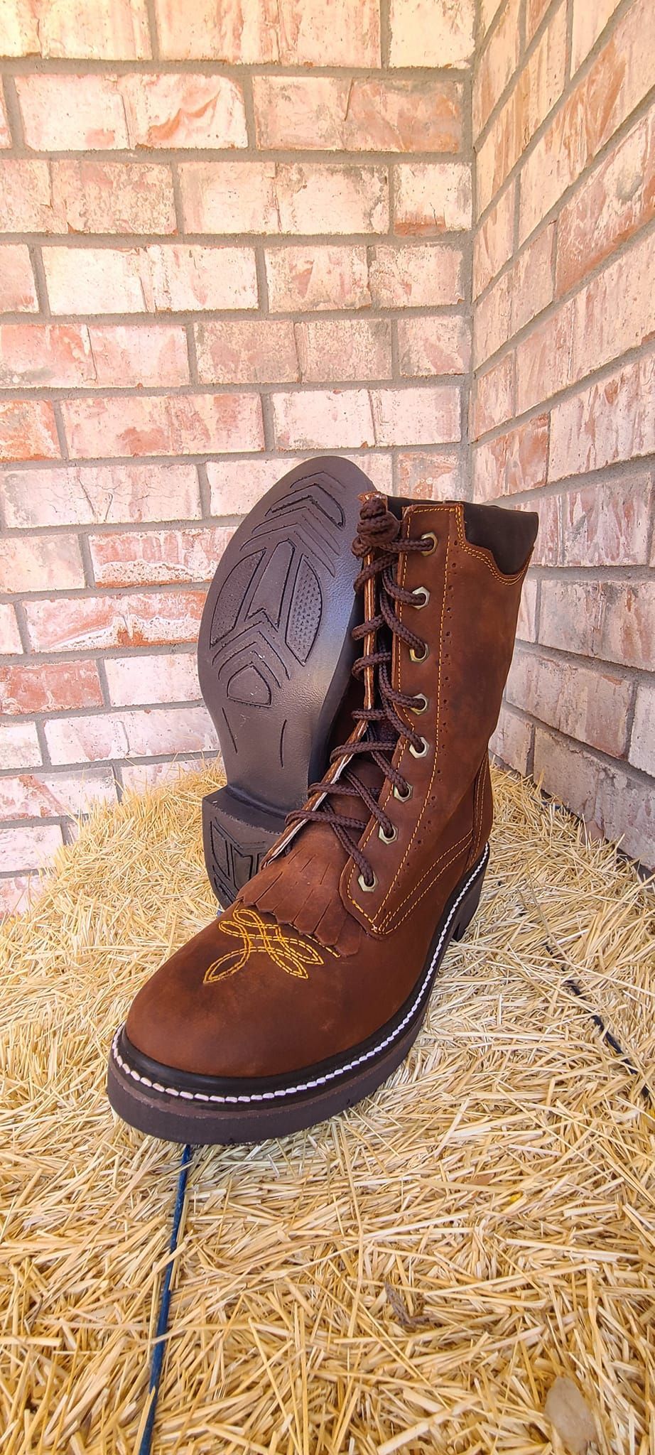 A pair of brown boots sitting on top of a pile of hay.