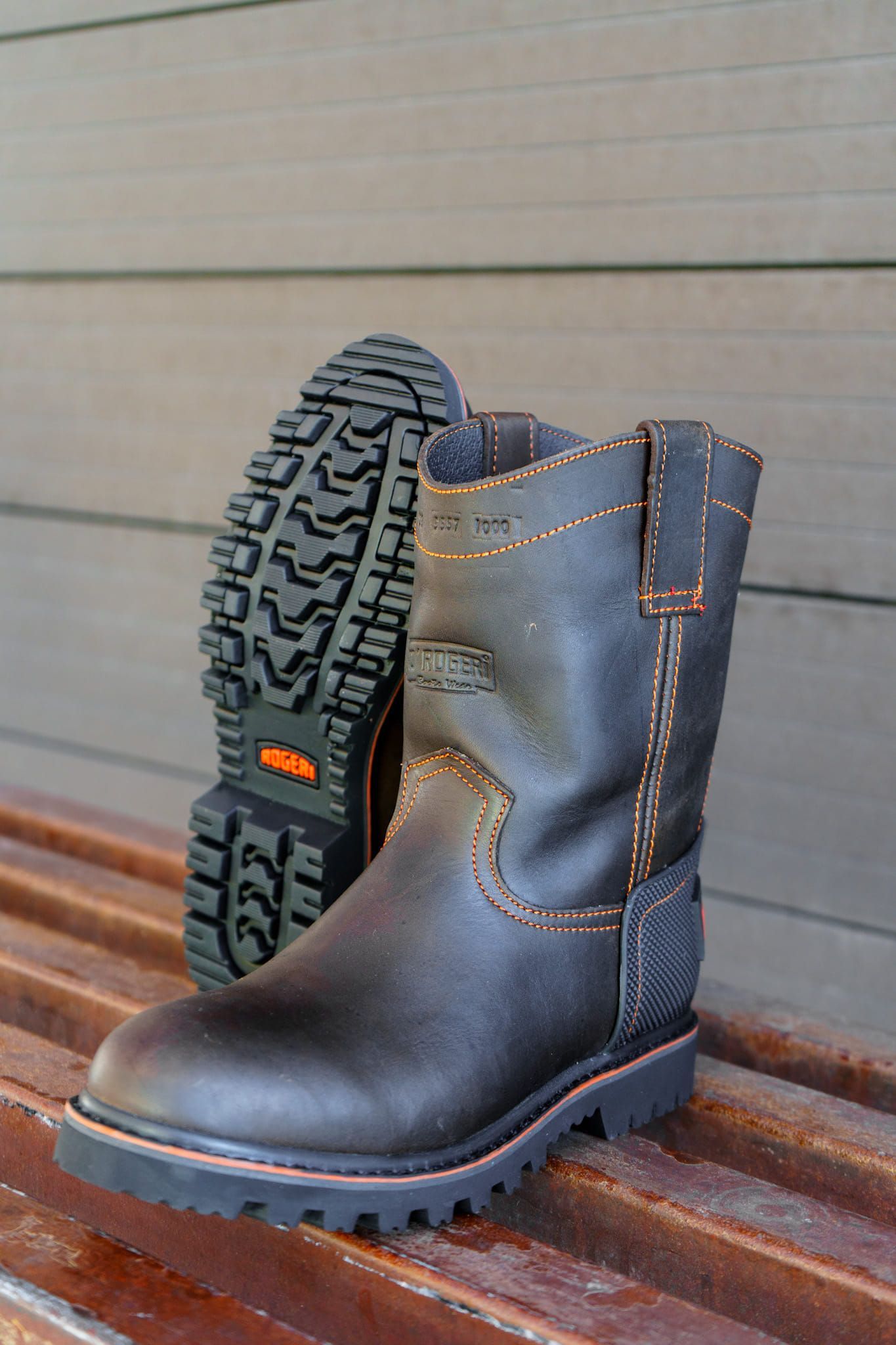 A pair of brown leather boots are sitting on a wooden bench.